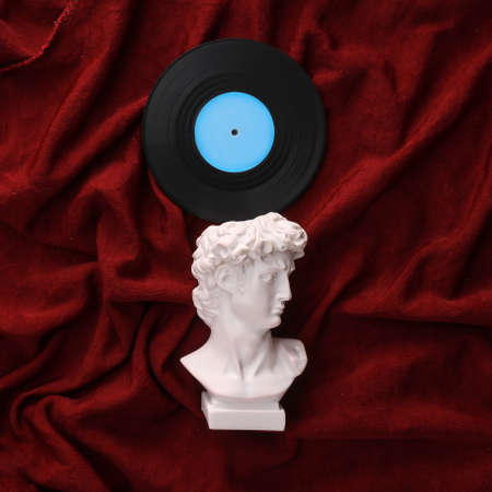 David plaster bust with vinyl record on red crumpled silk backgroundの写真素材