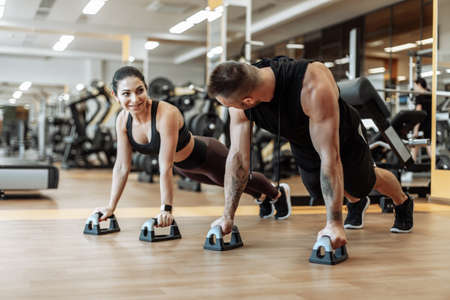 Workout together. Athletic man and woman are training doing push-ups in the gym. healthy lifestyle