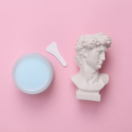David bust with a jar of cream on a pink background. skincare concept