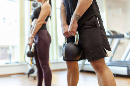 Athletic man and woman training together with kettlebells in modern gymの写真素材