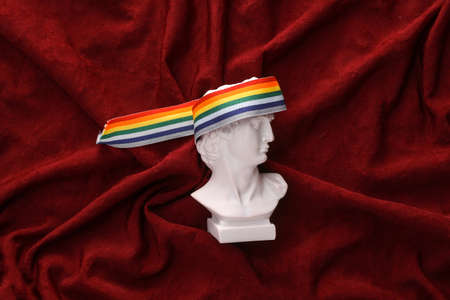David plaster bust with lgbt rainbow tape on red crumpled silk background