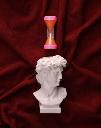 David plaster bust with hourglass on red crumpled silk background