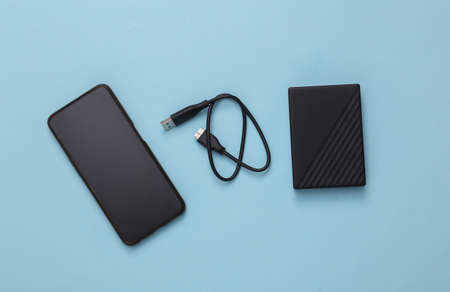 Smartphone with external hard drive on a blue backgroundの写真素材