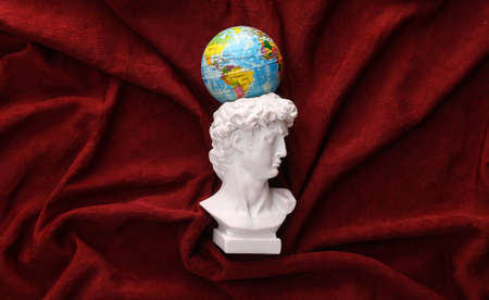 David plaster bust with globe on red crumpled silk backgroundの写真素材