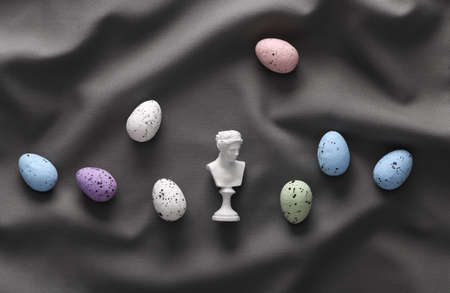 Venus plaster bust with colored easter eggs on gray crumpled silk background