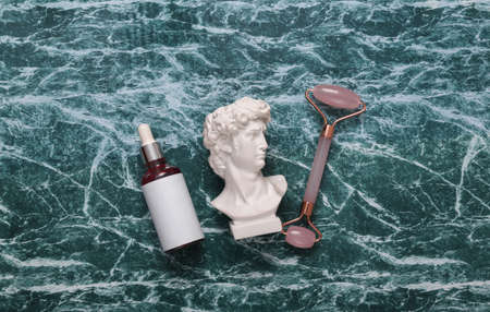 David plaster bust with beauty products on marble green surface