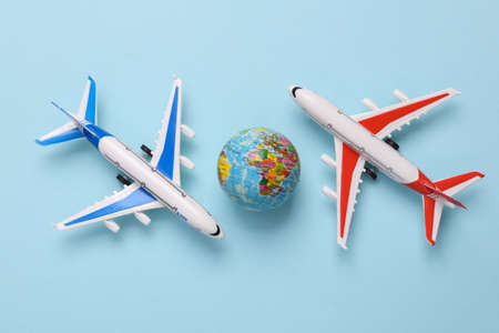 Toy model airplanes with globe on blue background. travel concept. Flat lay, top view
