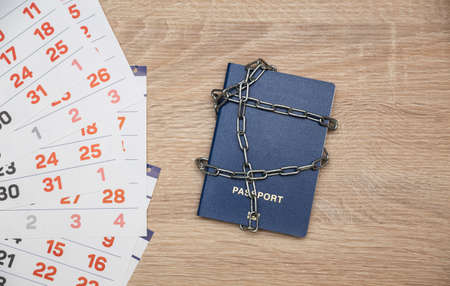Passport wrapped in a steel chain and a paper calendar on the tableの写真素材