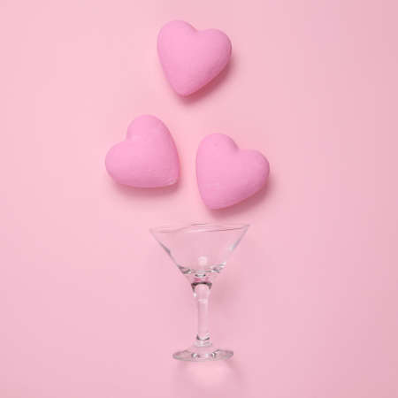 Cocktail glass with hearts on pink background. love concept. top view. flat layの写真素材