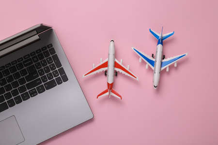 Model airplanes with laptop on pink background. travel concept. Flat lay, top view