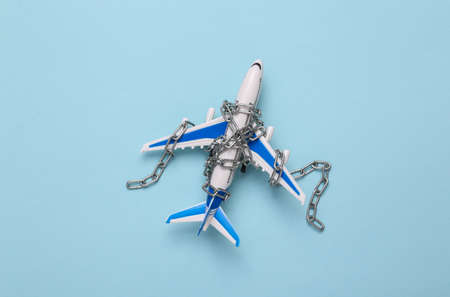 Air travel ban. Airplane wrapped in chain and on blue background. top view. flat lay