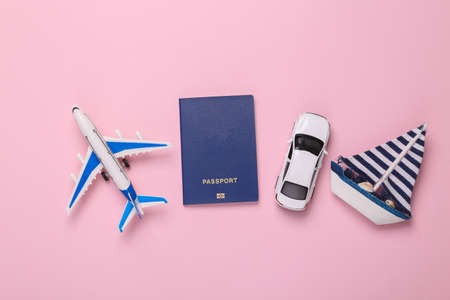Toy Passenger plane, car and sailboat, passport on pink background. transport. travel concept. top...