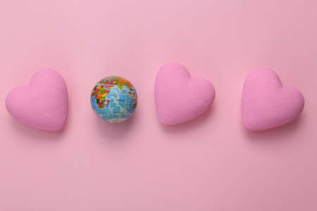 Globe with hearts on pink background. love concept. top viewの写真素材