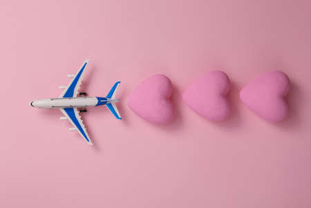 Toy air plane and hearts on pink blue background. Love, travel concept. top view. flat lay