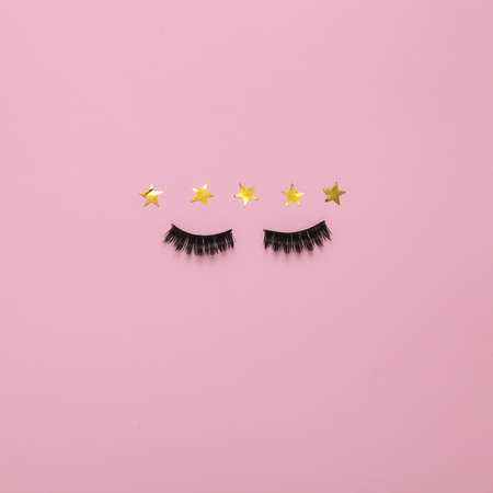 Excellent beauty service. False eyelashes with 5 gold stars on pink background. top view