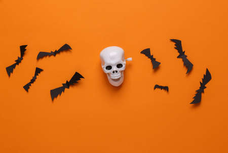 Halloween background with skeleton skull and bats on orange background. top view. flat layの写真素材
