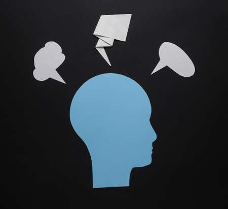Paper cut human head with blank dialog clouds on black background. Flow of ideas or questions