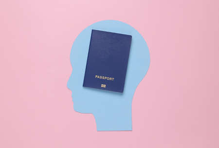 Paper-cut human head with a passport on a pink background.の写真素材