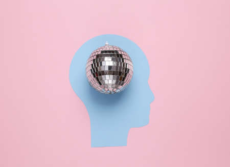 Paper cut human head with disco ball on pink background. party concept