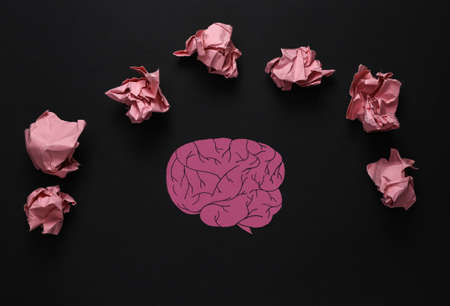 Paper-cut brain and crumpled ball of paper on black background. Lack of ideasの写真素材