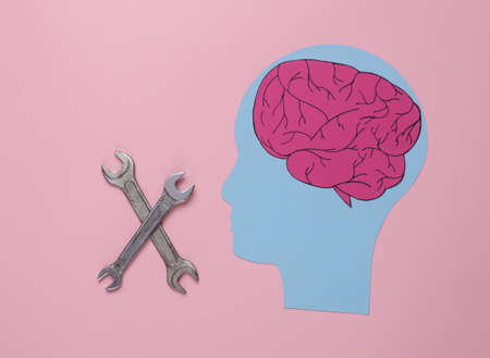 Paper-cut head with brain and wrenches on pink background. Mental health treatmentの写真素材