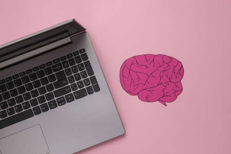 Laptop with paper brain on pink backgroundの写真素材