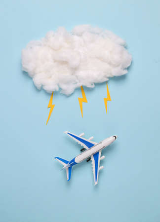 an airplane and a cloud with a thunderstorm on a blue background. Travel concept, bad weather for...