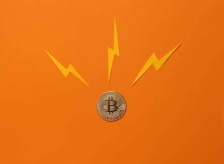 Golden bitcoin with lightning arrows on an orange background. financial crisis, cryptocurrencyの写真素材