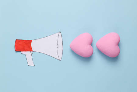 Paper cut cartoon megaphone with hearts on blue background. love conceptの写真素材