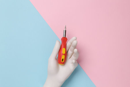 White hand holding a screwdriver on a blue-pink pastel backgroundの写真素材