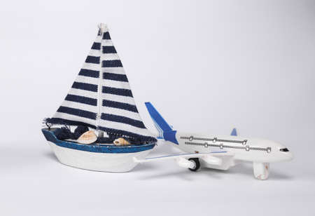 Model passenger plane and sailboat isolated on white background. Travel concept, transportation