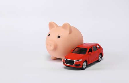 Small red car model with piggy bank isolated on white backgroundの写真素材