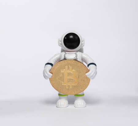 Astronaut toy model holding bitcoin isolated on white background
