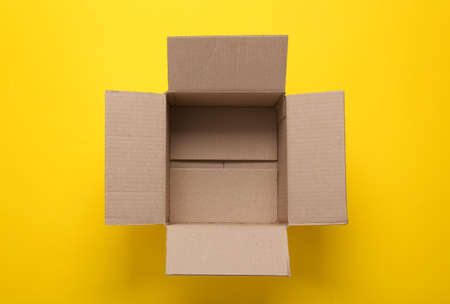 Open empty cardboard box on yellow background. top view
