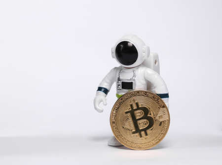 Astronaut toy model holding bitcoin isolated on white backgroundの写真素材