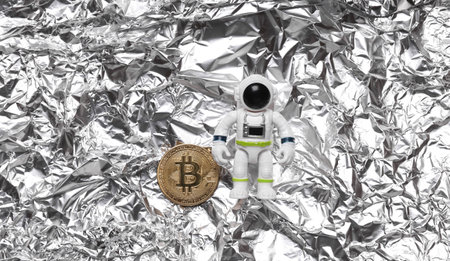 Astronaut toy model with bitcoin on foil. space mission