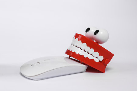 Clockwork joke jaw with pc mouse isolated on white backgroundの写真素材