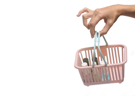 Female hand holding mini shopping basket with nail polish bottles isolated on white background.の写真素材