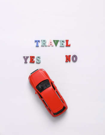 Travel yes or no. Toy car model on white background. Travel concept, flat lay
