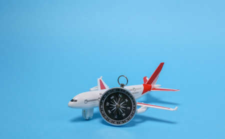Travel, voyage concept. Model of a passenger plane with compass on blue backgroundの写真素材