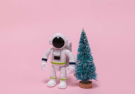 Astronaut in a spacesuit figurine with a Christmas tree on pink background.の写真素材