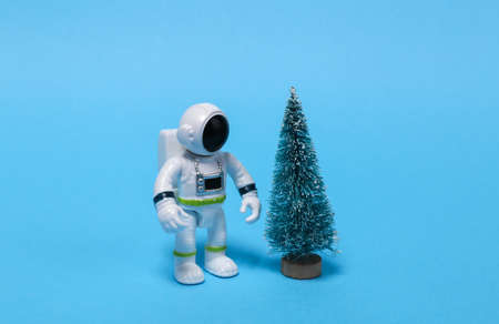 Astronaut in a spacesuit figurine with a Christmas tree on a blue background.の写真素材