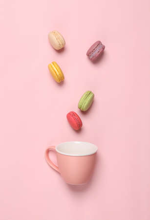 Ceramic tea cup with macaroons on pink background. Creative food and drink concept. flat layの写真素材