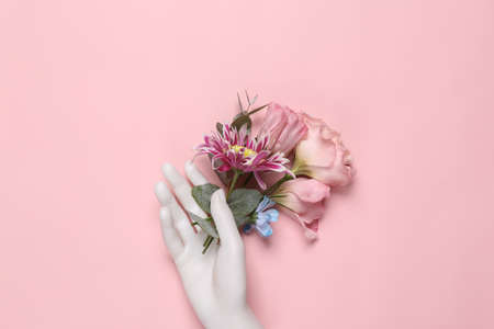 Beauty, love, romantic concept. Hand holding flowers on pink background. top view. flat layの写真素材