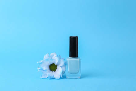 beauty still life. Blue Nail polish bottle with flower isolated on blue backgroundの写真素材