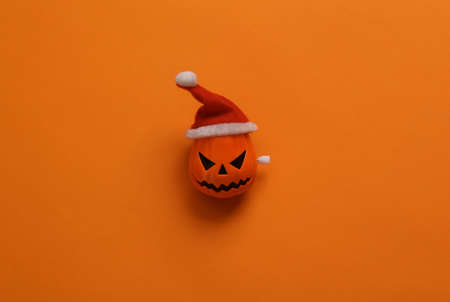 Minimal Halloween or Christmas still life. Clockwork head of jack o'lantern on orange background. top viewの写真素材