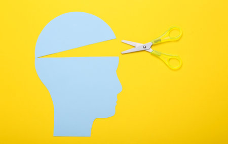 Open your mind, mental health concept, creative thinking. Paper silhouette of human head and scissors on a yellow backgroundの写真素材