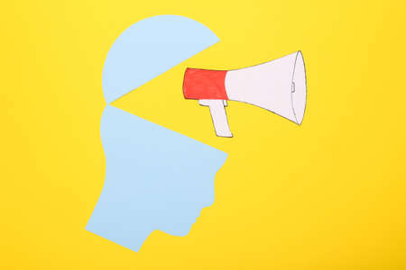 Open your mind, mental health concept, creative thinking. Paper silhouette of human head and megaphone on yellow backgroundの写真素材