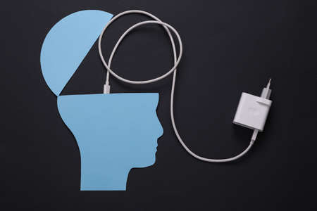 charge your brain. Open your mind, mental health concept, creative thinking. Paper silhouette of human head and charger on black backgroundの写真素材