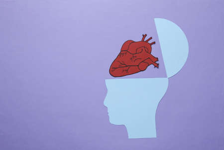 Open mind, medical concept. Silhouette of a human head with an anatomical heart on a lavender...